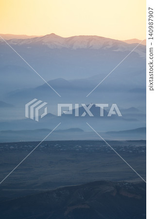 Valley surrounded by Caucasus mountains hills covered in fog and church on top of hill at sunset. Valley surrounded by Caucasus mountains hills covered in fog and church on top of hill at sunset. 140987907