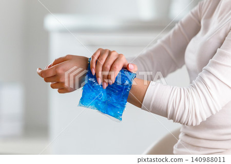 Woman applying cold compress to a her painful wrist Woman applying cold compress to a her painful wrist 140988011