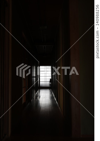 A long, dimly lit corridor with no windows. An old Japanese house. Light streams in from a window at the back. A long, dimly lit corridor with no windows. An old Japanese house. Light streams in from a window at the back. 140988256