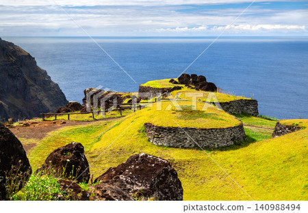 Ancient stone houses of the Orongo ceremonial village on the cliff edge of Easter Island, Chile, overlooking the Pacific Ocean. Ancient stone houses of the Orongo ceremonial village on the cliff edge of Easter Island, Chile, overlooking the Pacific Ocean. 140988494