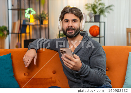 Indian man with wireless headphones listens playlist dances positive mood chill music session vibe Indian man with wireless headphones listens playlist dances positive mood chill music session vibe 140988582