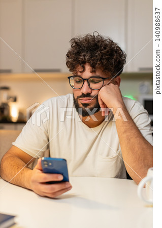 Arabian man bored scrolls smartphone news at night stressed demotivated sighs needs break from news Arabian man bored scrolls smartphone news at night stressed demotivated sighs needs break from news 140988637