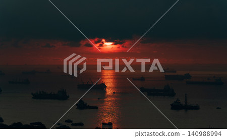 旭日東升,照耀著新加坡海峽,一支船隊正在航行。 旭日東升,照耀著新加坡海峽,一支船隊正在航行。 140988994