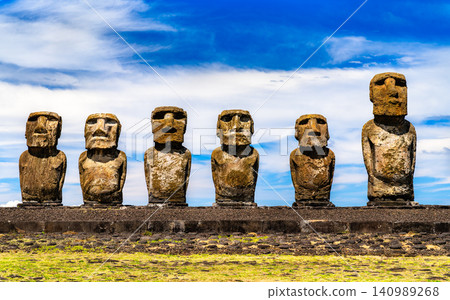 Row of ancient stone moai statues standing at Ahu Tongariki under a blue sky on Easter Island, Chile. Row of ancient stone moai statues standing at Ahu Tongariki under a blue sky on Easter Island, Chile. 140989268