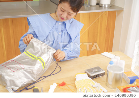 A woman checking disaster prevention goods A woman checking disaster prevention goods 140990390