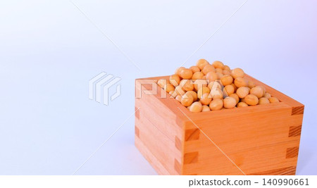 A wooden measuring cup and soybeans for Setsubun are placed against a white background. A wooden measuring cup and soybeans for Setsubun are placed against a white background. 140990661