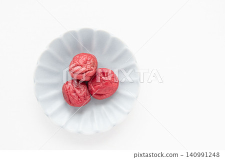 一個小碟子裡放著一顆鮮紅的醃梅子。 一個小碟子裡放著一顆鮮紅的醃梅子。 140991248