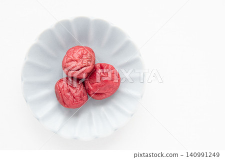 A bright red pickled plum placed on a small plate A bright red pickled plum placed on a small plate 140991249