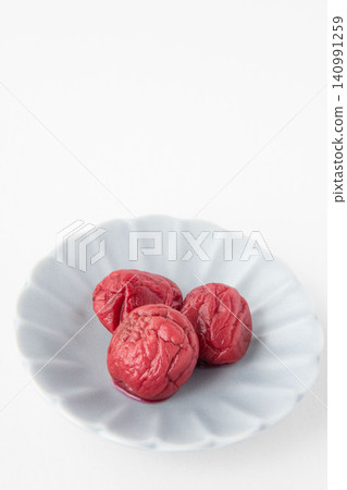 A bright red pickled plum placed on a small plate A bright red pickled plum placed on a small plate 140991259