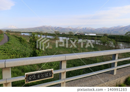 In spring in Hokkaido, the Niseko mountain range and Raiden Coast viewed from the vicinity of Horikabu River in Kyowa Town, at the base of the Shakotan Peninsula in Shiribeshi, at dusk. In spring in Hokkaido, the Niseko mountain range and Raiden Coast viewed from the vicinity of Horikabu River in Kyowa Town, at the base of the Shakotan Peninsula in Shiribeshi, at dusk. 140991283
