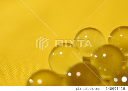 A transparent glass ball against a yellow background. A transparent glass ball against a yellow background. 140991416