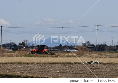 A rural landscape in Kuki City, Saitama Prefecture, with a large tractor parked nearby. 140991629