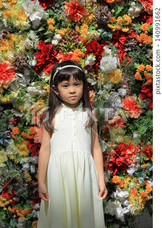 A female elementary school student (7 years old) stands in front of a flower wall. A female elementary school student (7 years old) stands in front of a flower wall. 140991662