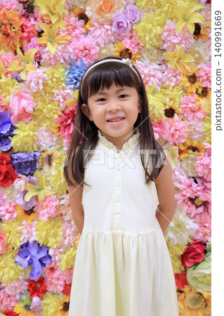 A female elementary school student (7 years old) stands in front of a flower wall. A female elementary school student (7 years old) stands in front of a flower wall. 140991669