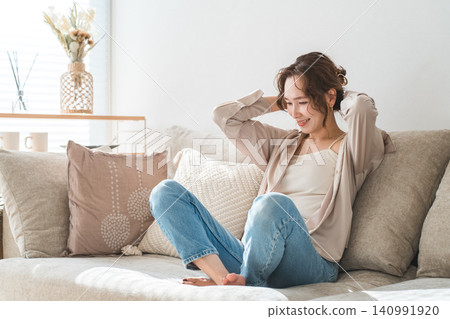 Stylish housewife Asian woman relaxing on the sofa in the living room Stylish housewife Asian woman relaxing on the sofa in the living room 140991920