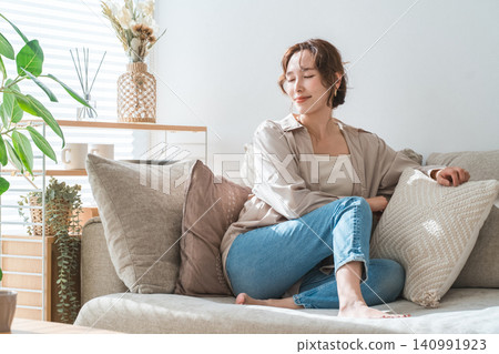 一位時尚的亞洲家庭主婦在客廳的沙發上放鬆休息 140991923