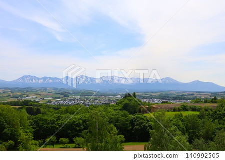 六月的北海道,春天的北海道,初夏的北海道:從美瑛市西北丘陵展望公園眺望美瑛市和十勝山脈,美瑛市是一個丘陵起伏的小鎮。 六月的北海道,春天的北海道,初夏的北海道:從美瑛市西北丘陵展望公園眺望美瑛市和十勝山脈,美瑛市是一個丘陵起伏的小鎮。 140992505