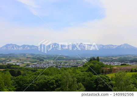六月的北海道，春天的北海道，初夏的北海道：從美瑛市西北丘陵展望公園眺望美瑛市和十勝山脈，美瑛市是一個丘陵起伏的小鎮。 140992506