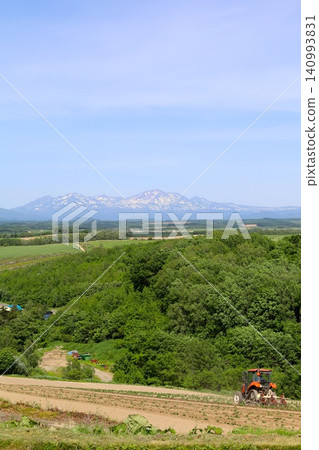 六月的北海道,春天的北海道,初夏的北海道:從美瑛市西北丘陵展望公園眺望美瑛市和十勝山脈,美瑛市是一個丘陵起伏的小鎮。 六月的北海道,春天的北海道,初夏的北海道:從美瑛市西北丘陵展望公園眺望美瑛市和十勝山脈,美瑛市是一個丘陵起伏的小鎮。 140993831