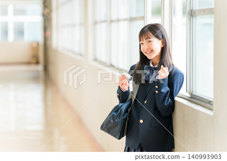 一個穿著西裝外套的女孩在學校走廊上學習,同時看著一本詞彙書 一個穿著西裝外套的女孩在學校走廊上學習,同時看著一本詞彙書 140993903