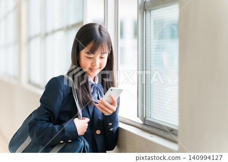 A smiling high school girl using her smartphone in the school hallway (filtering, internet literacy) A smiling high school girl using her smartphone in the school hallway (filtering, internet literacy) 140994127
