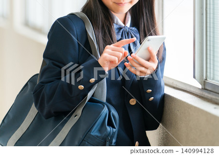 一位微笑的高中女生在學校走廊使用智慧型手機（過濾訊息，網路素養） 140994128