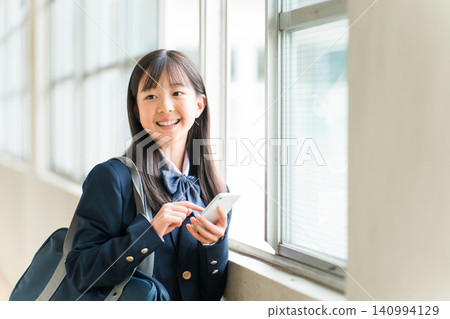 A smiling high school girl using her smartphone in the school hallway (filtering, internet literacy) A smiling high school girl using her smartphone in the school hallway (filtering, internet literacy) 140994129