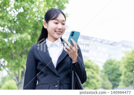一位身穿職業套裝的女士正在使用智慧型手機找工作。 140994477