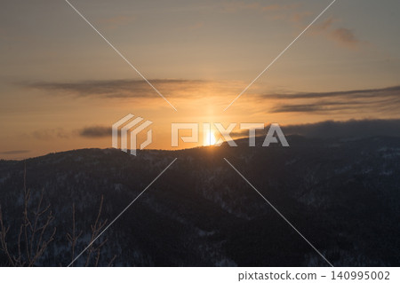 Sunset sinking below the ridgeline and sun pillar Sunset sinking below the ridgeline and sun pillar 140995002