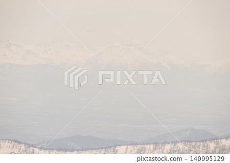 A view of snow-capped mountains shrouded in spring mist. 140995129