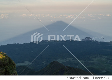 山巒金字塔聳立於海面和雲層之上。 山巒金字塔聳立於海面和雲層之上。 140995327