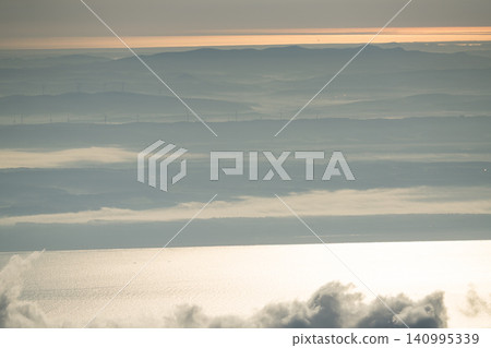 A sea of clouds and a band of golden light shining on the hills A sea of clouds and a band of golden light shining on the hills 140995339