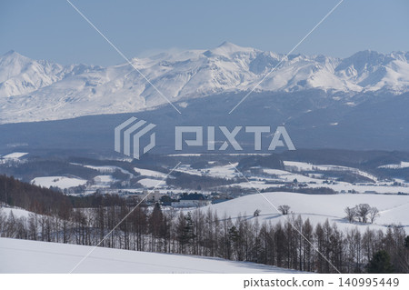 Snow-capped mountain ranges towering over winter valleys Snow-capped mountain ranges towering over winter valleys 140995449