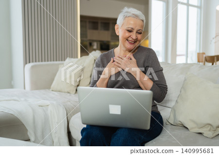 Happy middle aged senior woman siting with laptop talking on video call with friends family. Laughing mature old senior grandmother having fun talking speaking with grown up children online Happy middle aged senior woman siting with laptop talking on video call with friends family. Laughing mature old senior grandmother having fun talking speaking with grown up children online 140995681