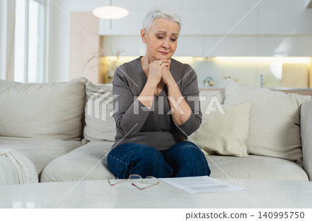 Sad tired ill sick lonely disappointed older senior woman sitting at home alone. Unhappy mature grandmother experiencing grief relative death bad news. Stressed elder lady suffering from loneliness Sad tired ill sick lonely disappointed older senior woman sitting at home alone. Unhappy mature grandmother experiencing grief relative death bad news. Stressed elder lady suffering from loneliness 140995750