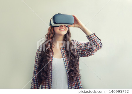 Smile young woman wearing using virtual reality VR glasses helmet headset on white background. Smartphone using with virtual reality goggles. Technology, simulation, hi-tech, videogame concept Smile young woman wearing using virtual reality VR glasses helmet headset on white background. Smartphone using with virtual reality goggles. Technology, simulation, hi-tech, videogame concept 140995752
