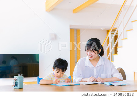 一位母親正在輔導她上小學的兒子。 一位母親正在輔導她上小學的兒子。 140995838