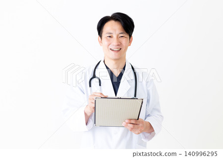 A middle-aged male doctor in a white coat holding a binder containing patient charts. A middle-aged male doctor in a white coat holding a binder containing patient charts. 140996295
