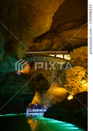 Underground river, pier, bridge illuminated by light in Yellow Dragon Cave near Zhangjiajie, China Underground river, pier, bridge illuminated by light in Yellow Dragon Cave near Zhangjiajie, China 140996833