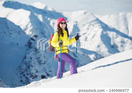 Solo Female Hiker With Trekking Poles on Snowy Mountain Ascent in Bright Clothing Solo Female Hiker With Trekking Poles on Snowy Mountain Ascent in Bright Clothing 140996977