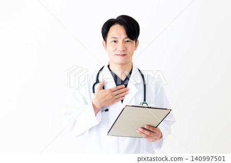 A middle-aged male doctor in a white coat, holding a binder of medical records, places his hand on his chest. 140997501