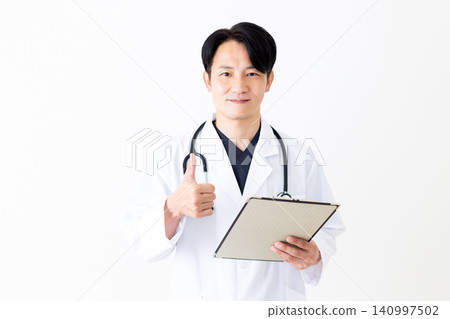 一位身穿白大褂的中年男醫生拿著裝有病人病歷的活頁夾,豎起大拇指,做出勝利的手勢。 一位身穿白大褂的中年男醫生拿著裝有病人病歷的活頁夾,豎起大拇指,做出勝利的手勢。 140997502