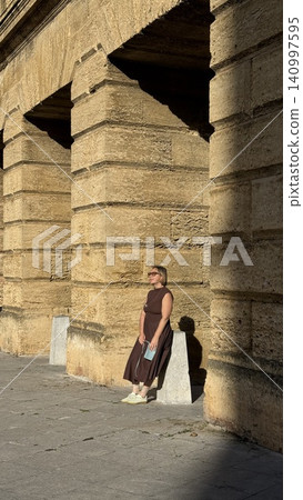 Woman Relaxing Against Stone Wall in Sunlight 140997595