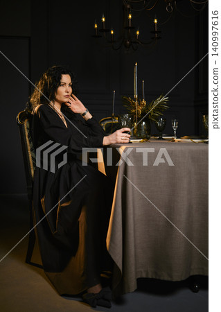 A woman sits at a table in a dimly lit room A woman sits at a table in a dimly lit room 140997616