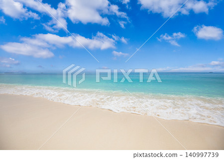 Calm turquoise sea meeting soft white sand shore. Bright blue sky over a tranquil tropical beach. Pristine paradise scene for background design copy space Calm turquoise sea meeting soft white sand shore. Bright blue sky over a tranquil tropical beach. Pristine paradise scene for background design copy space 140997739