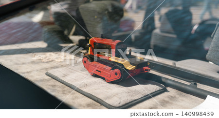 Toy construction vehicle inside classic car window. 140998439