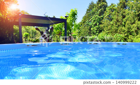 Outdoor swimming pool in a garden with lawn, plants and trees. Outdoor swimming pool in a garden with lawn, plants and trees. 140999222