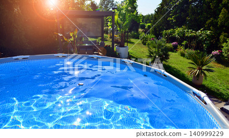 Outdoor swimming pool in a garden with lawn, plants and trees. Outdoor swimming pool in a garden with lawn, plants and trees. 140999229