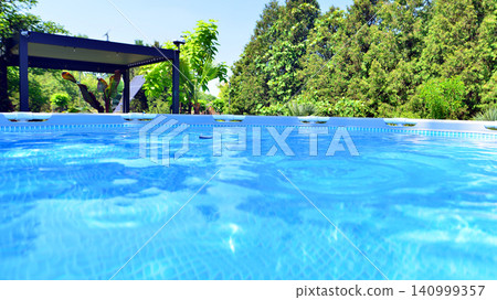 Outdoor swimming pool in a garden with plants and trees. Outdoor swimming pool in a garden with plants and trees. 140999357