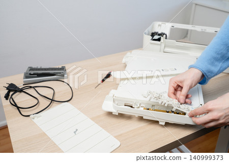 Printer And Scanner Repair On Desk With Hands, Tools And Disassembled Parts By Technician Printer And Scanner Repair On Desk With Hands, Tools And Disassembled Parts By Technician 140999373
